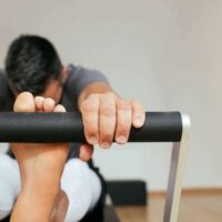 Sole and hands of a sportsman doing pilates exercise on reformer machine.